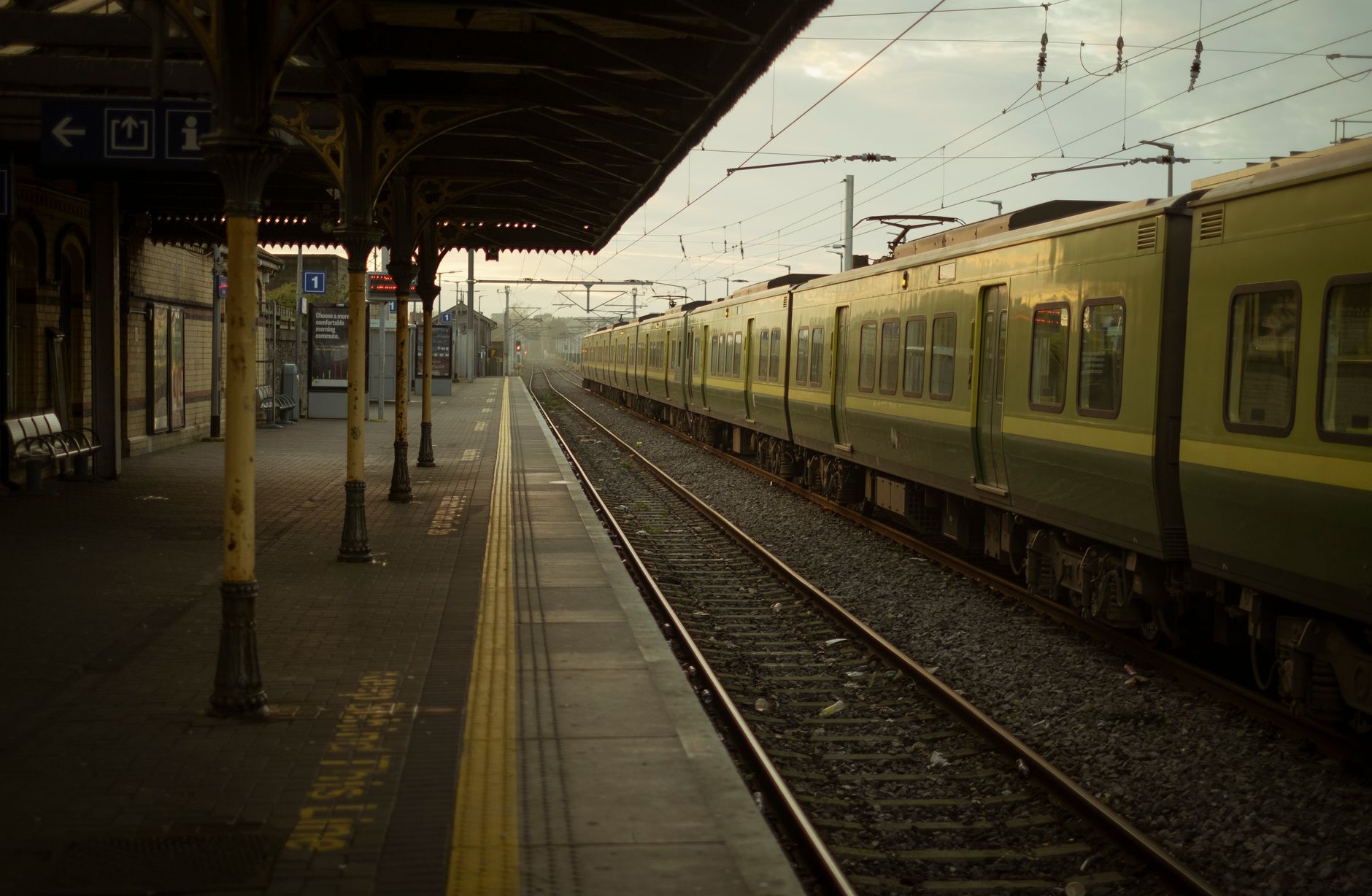 Commuters waiting on a busy British train station platform — the backdrop for famous train station announcers UK passengers have come to love
