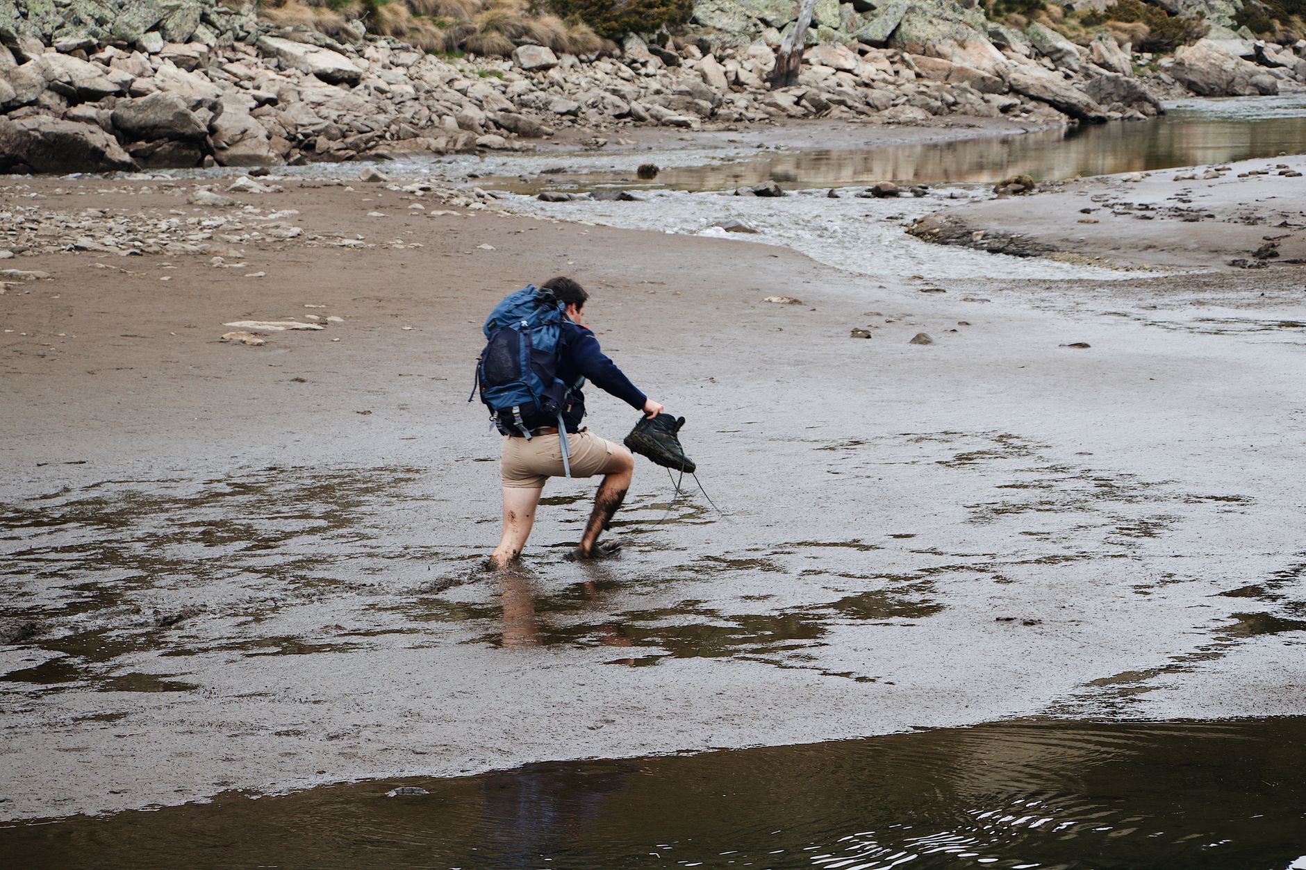 Mud-covered fell running shoes on a Pennine stone wall, typical of the unsponsored fell running online following aesthetic